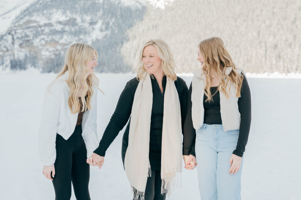 Two daughters and mother laughing while posing for a photo in Lake Louise
