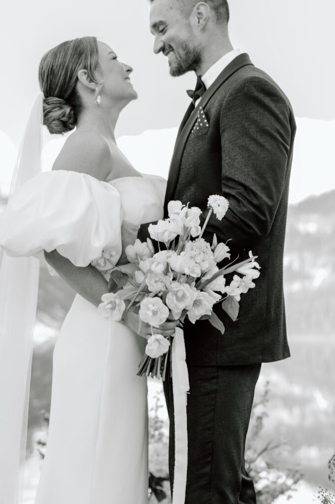 black-and-white-bride-and-groom-smiling-holding-bouquet-styled-lake-louise-wedding-banff-wedding-photography
