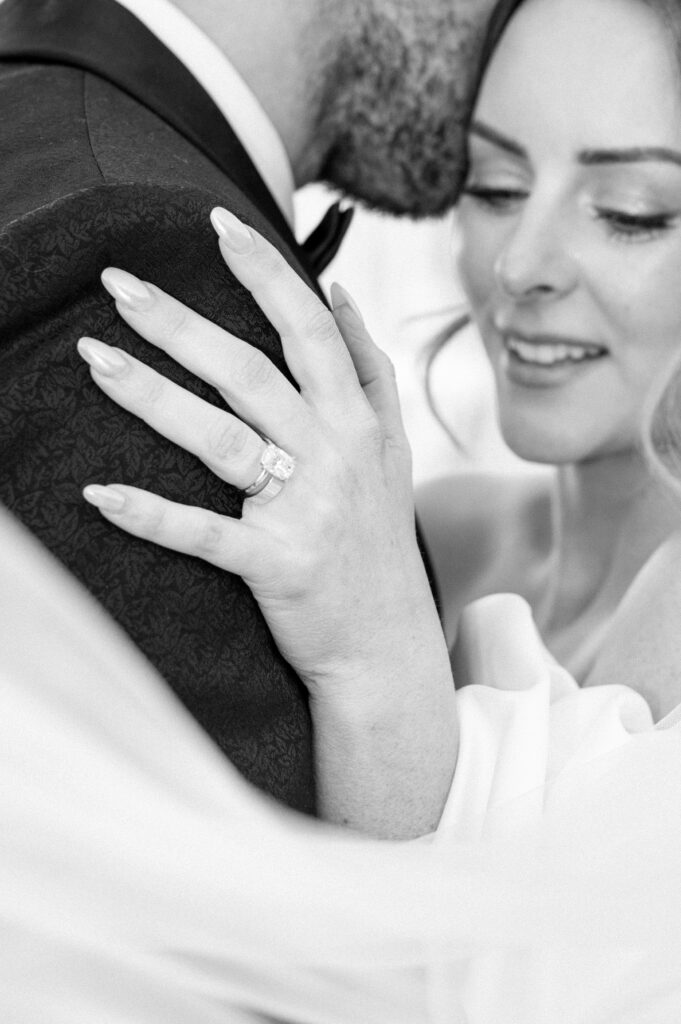 black-and-white-close-up-brides-ring-hand-on-grooms-shoulder-styled-lake-louise-wedding-detail-banff-wedding-photography