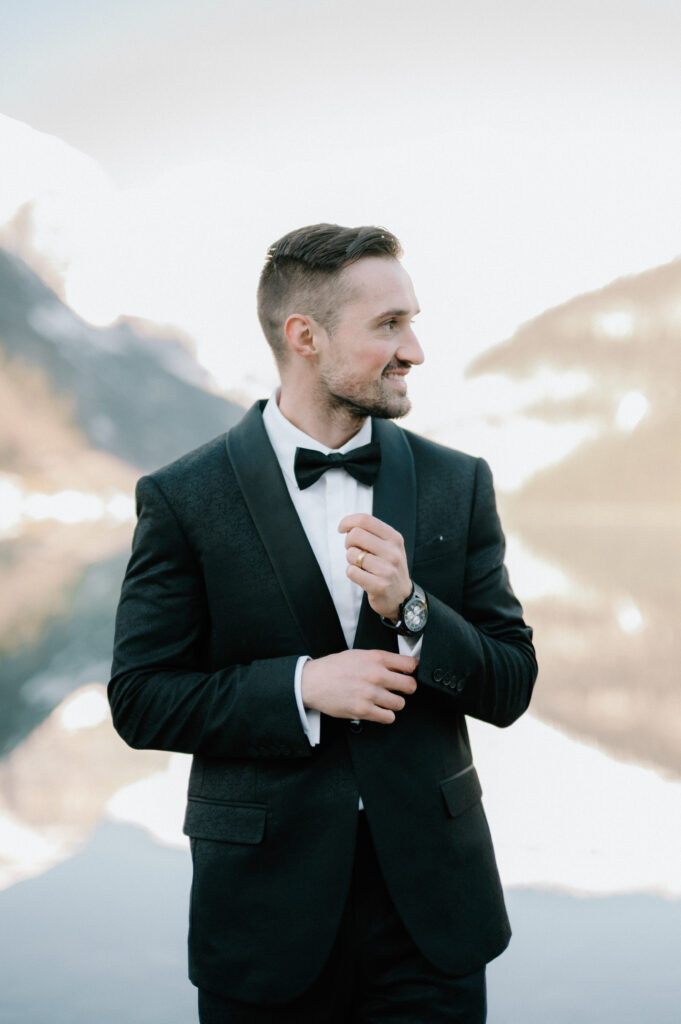 groom-portrait-in-black-tux-at-styled-lake-louise-wedding-with-mountain-backdrop-banff-wedding-photography